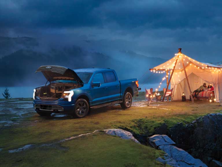 A F-150 Lightning® outside powering the lights at a campsite.