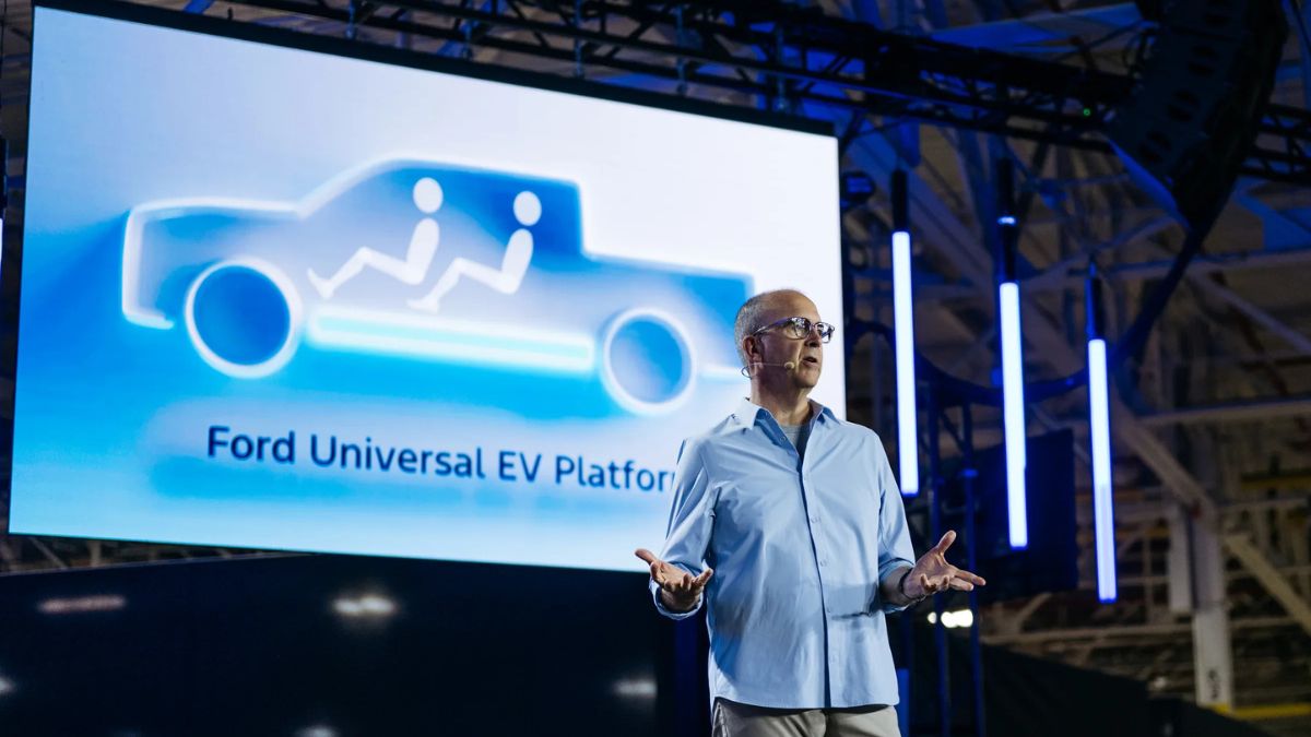 Ford Official Standing on Stage in Front of Ford Universal EV Platform Screen