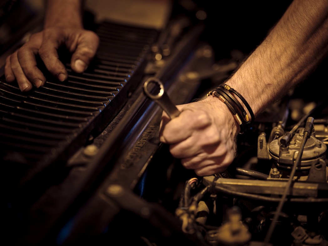 Person with a wrench working on a car engine