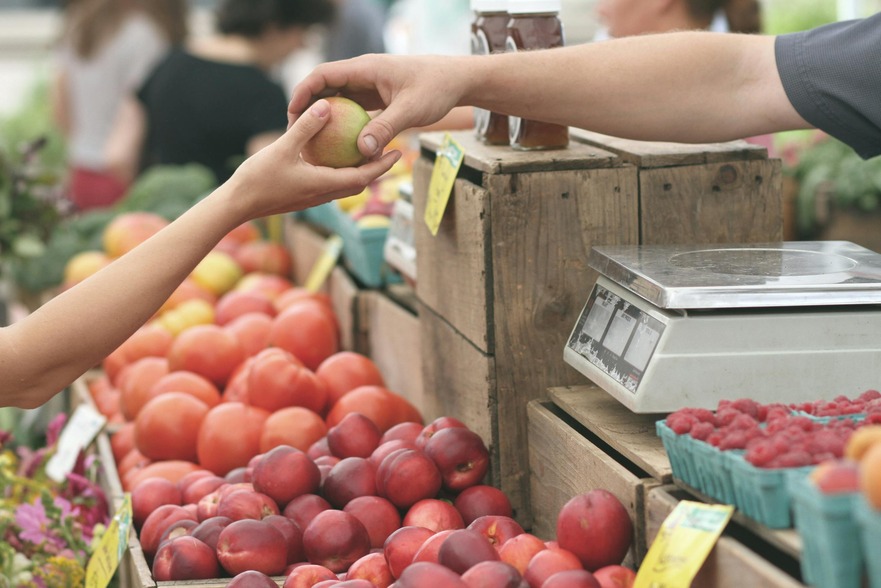 Person handing fruit to a buyer at a farmers market