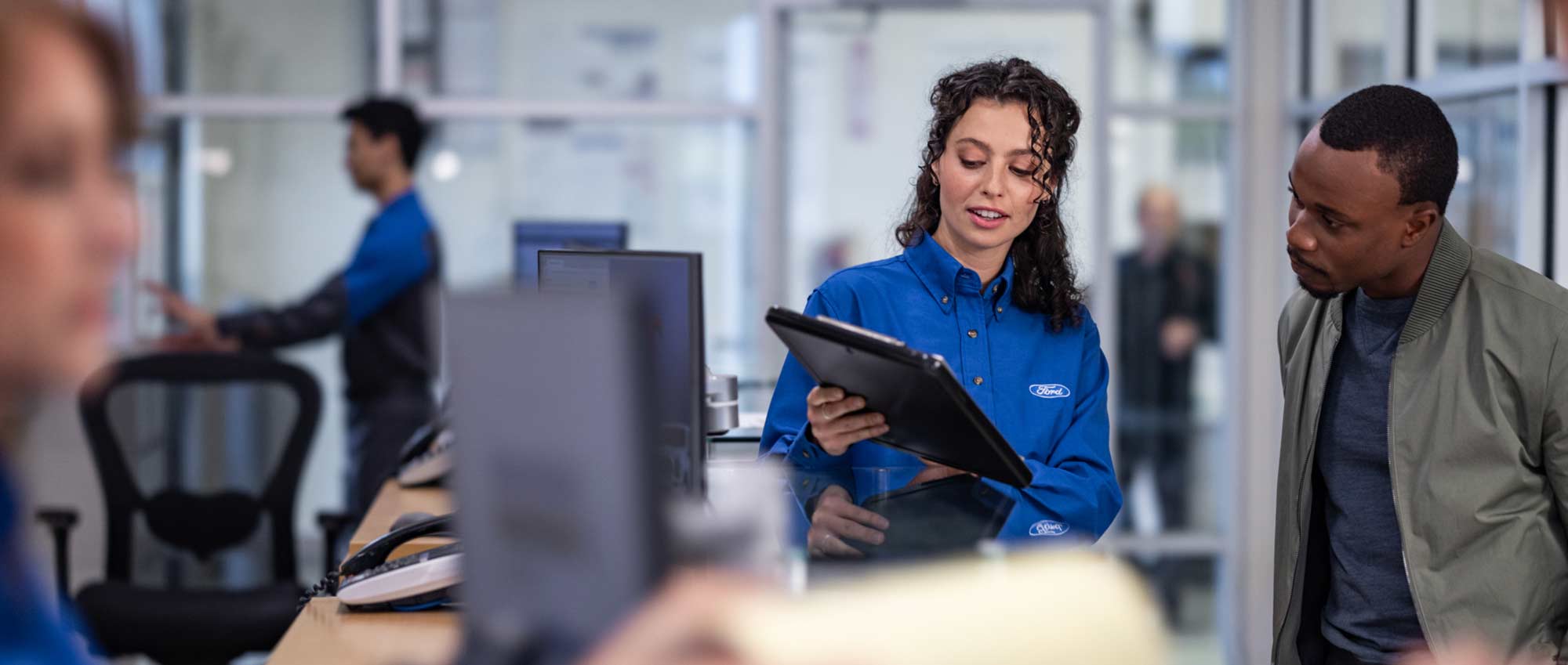 A Ford employee showing a customer information on their tablet.