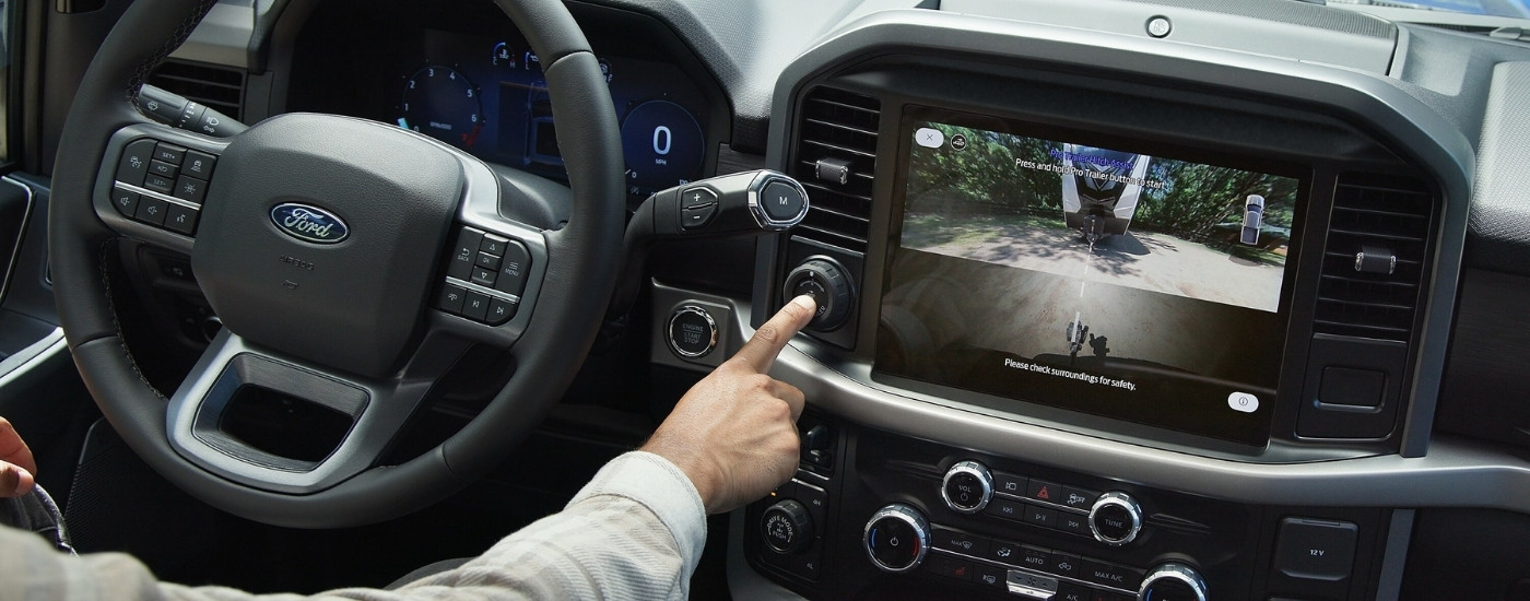 Person pushing a button in a 2025 Ford F-150.