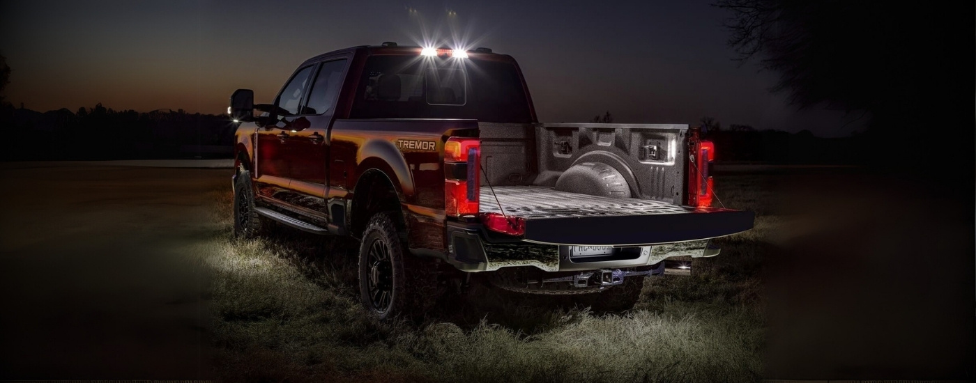 A red 2025 Ford F-250 Lariat Tremor at night parked on a field.