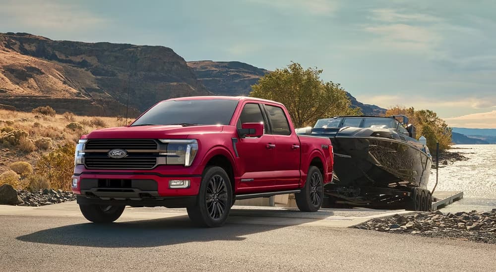 Red 2026 Ford F-150 towing a boat out of a lake