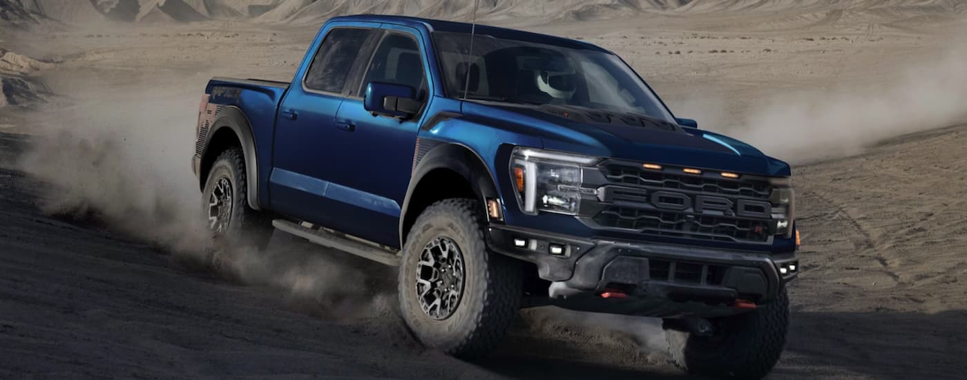 A blue 2025 Ford F 150 Raptor off-roading in dirt