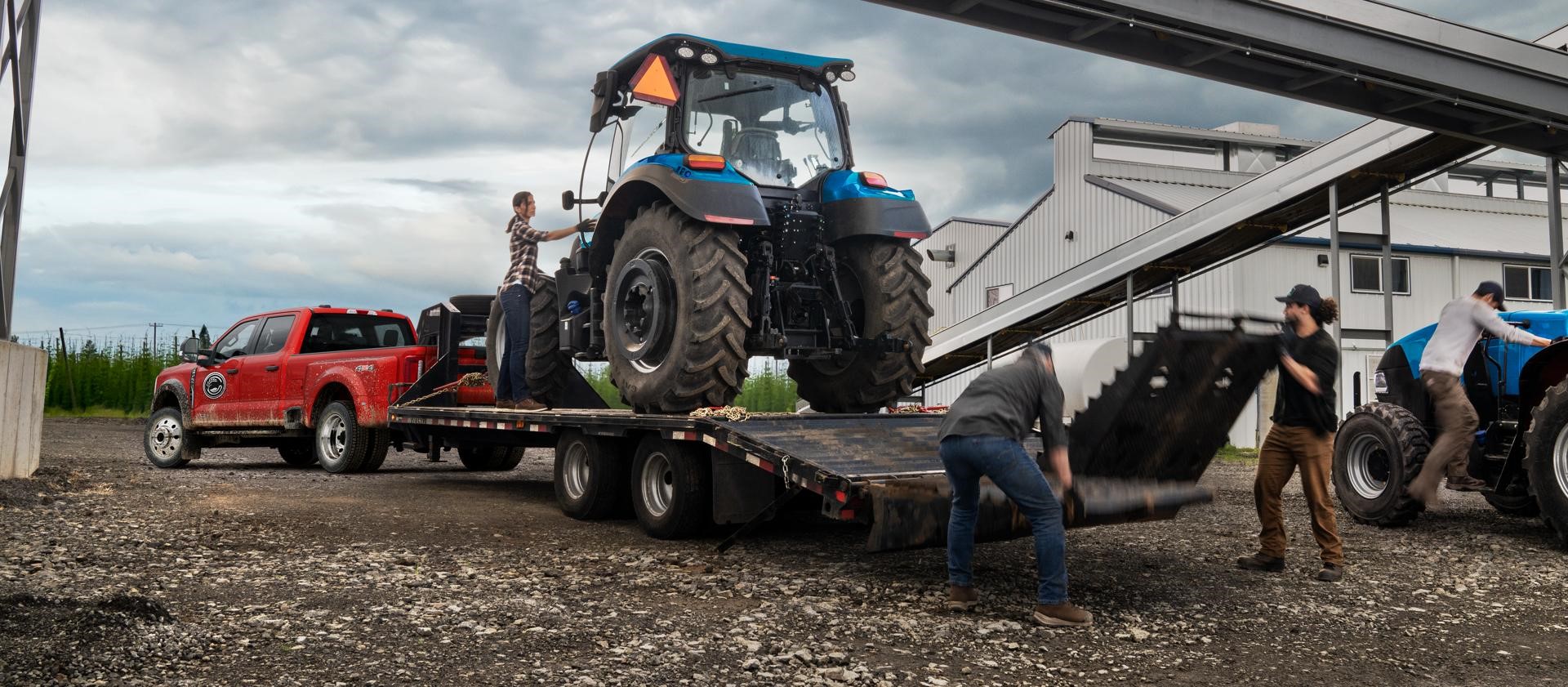 People loading a tractor behind the 2026 Ford F-250SD