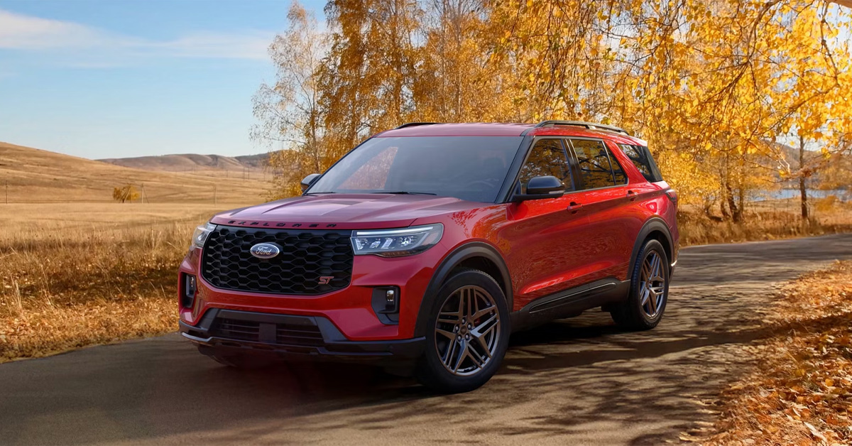 2026 Ford Explorer ST driving on a road with autumn trees.