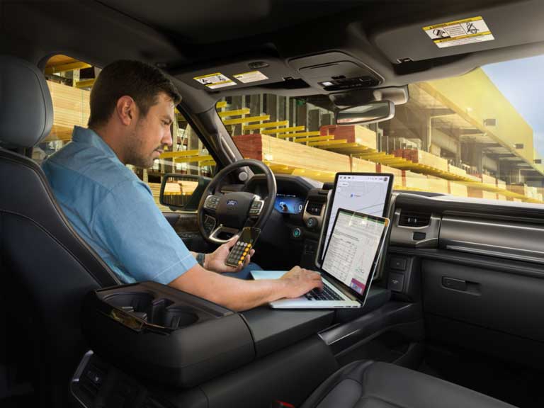 A man in his F-150 Lightning® working on a laptop.