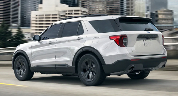 A 2021 Ford Explorer being driven down the highway with a cityscape in the background