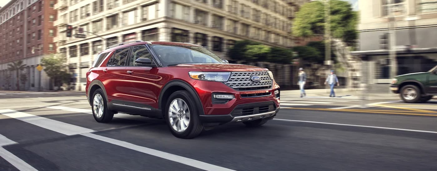 A red 2022 Ford Explorer Limited is shown driving on a city street. 