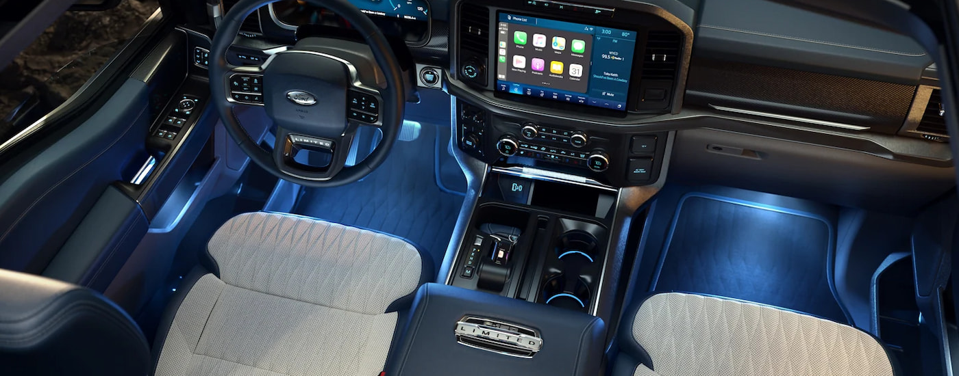 The black and tan interior of a 2022 Ford F-150 Limited shows the steering wheel and center console.