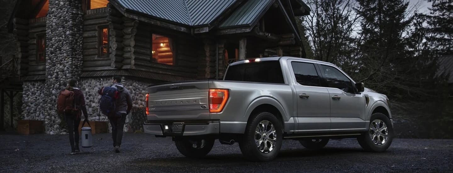 A silver 2022 Ford F-150 Platinum is shown from the rear parked near a cabin.