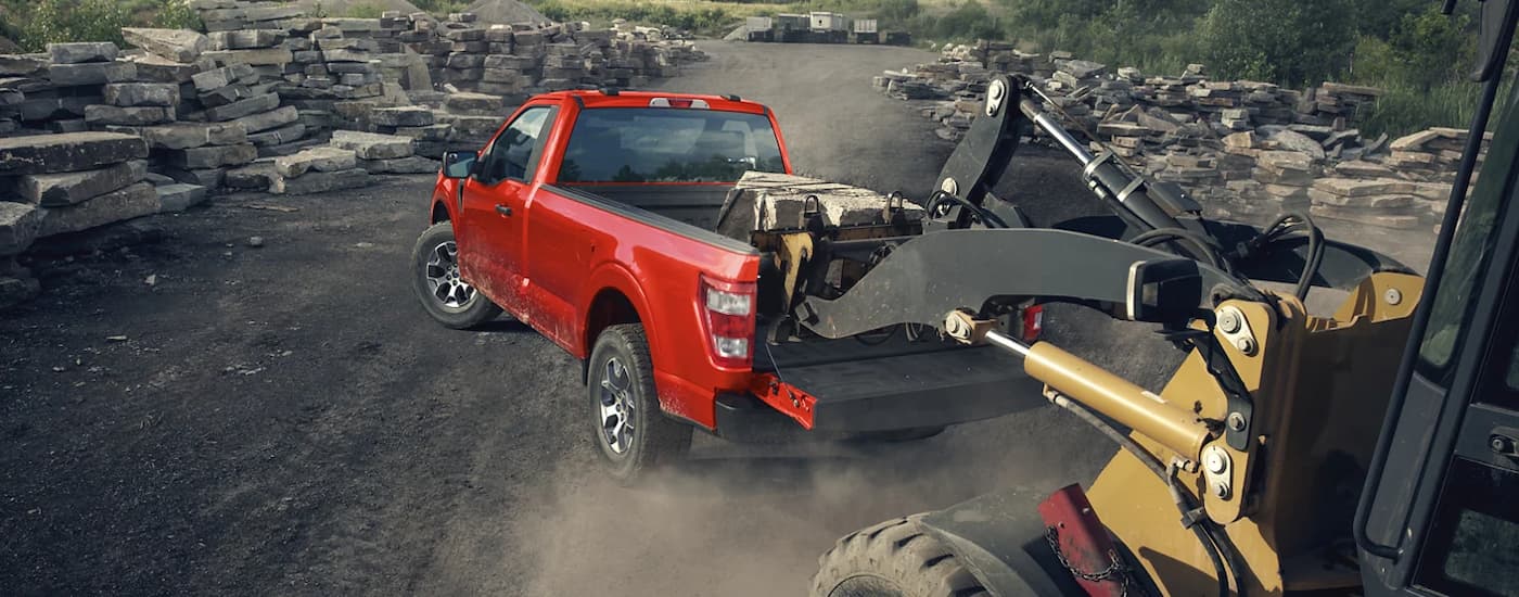 A red 2022 Ford F-150 XL is shown near heavy machinery.