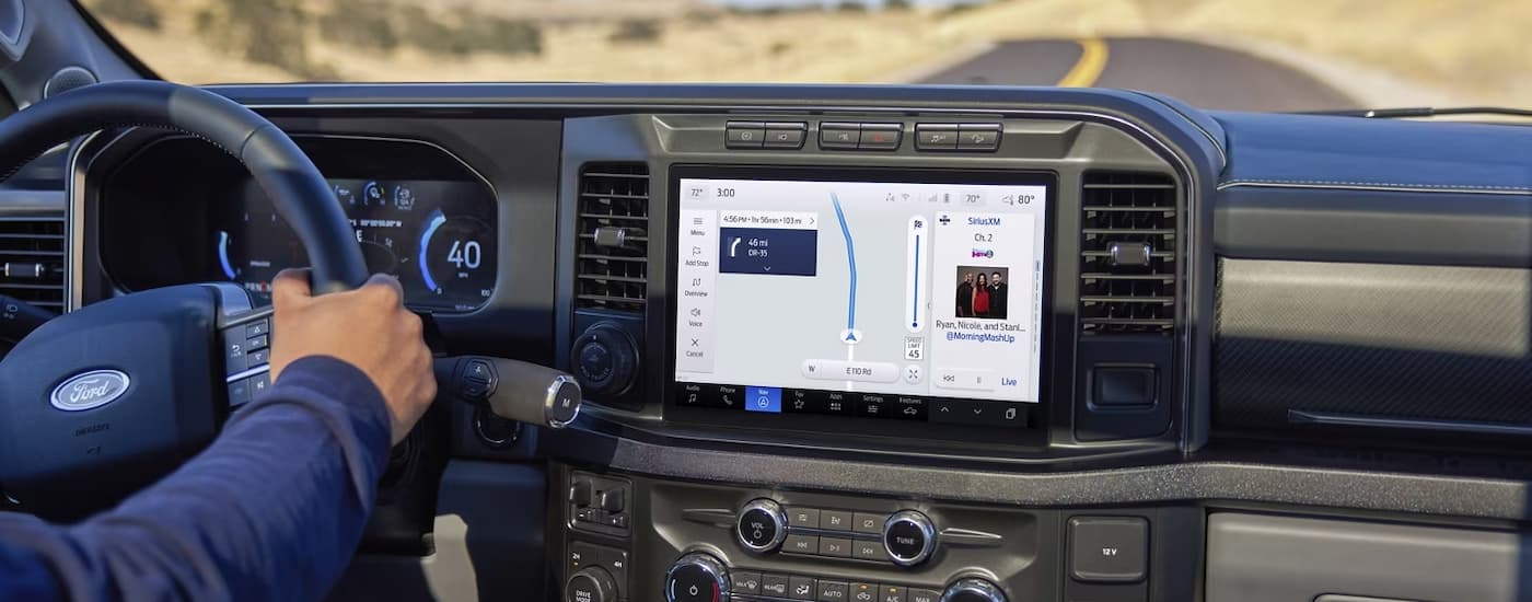 A person is shown driving a 2023 Ford F-250 while using the map feature on the infotainment screen.