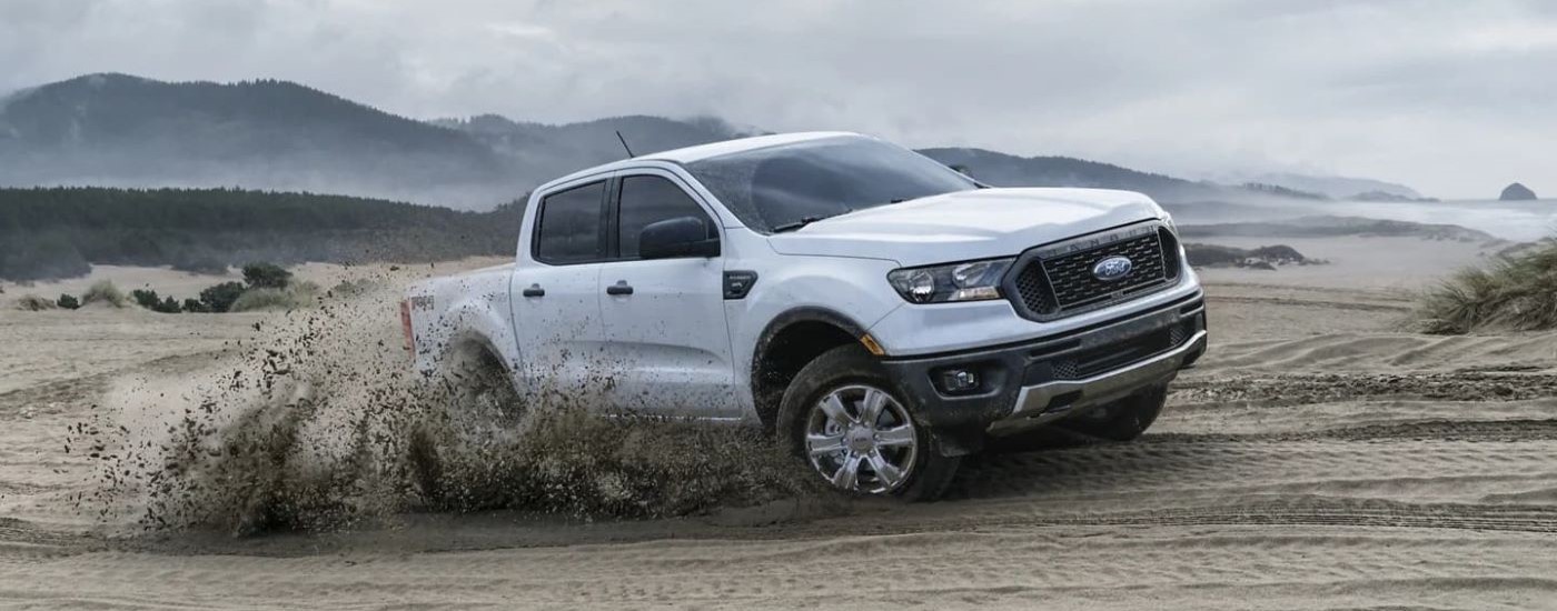 A white 2023 Ford Ranger Fx4 is shown kicking up dirt.