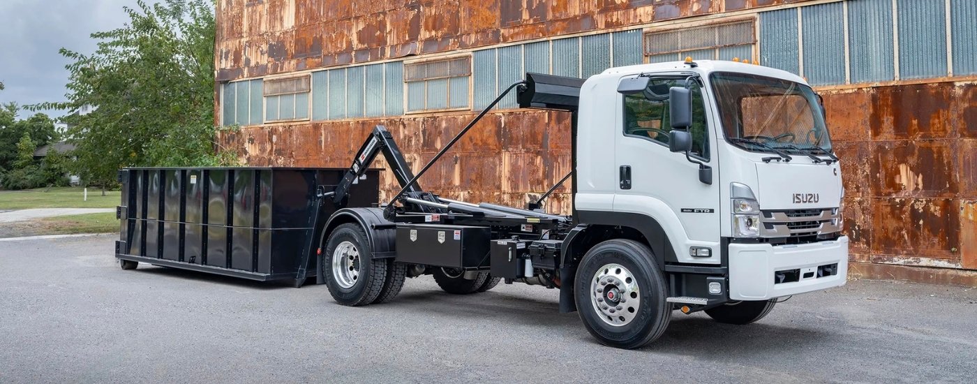White 2026 Isuzu FTR parked near a rusty building