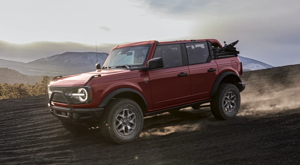 A red 2021 Ford Bronco is shown from the side driving in the mountains.