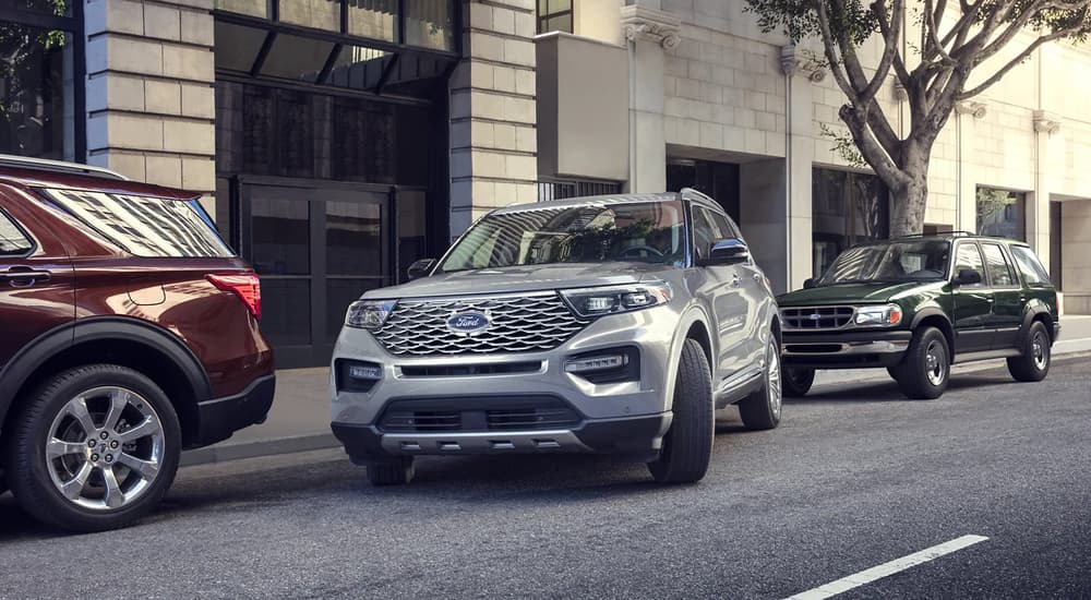 A silver 2023 Ford Explorer parallel parking on the side of a city street.