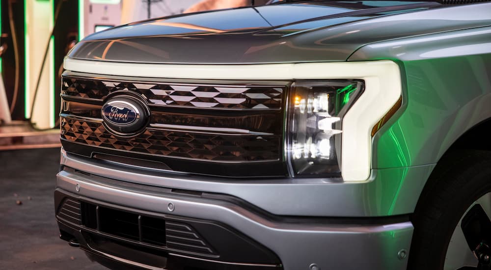 A close-up of the grille on a 2022 Ford F-150 Lightning reflecting green light from nearby