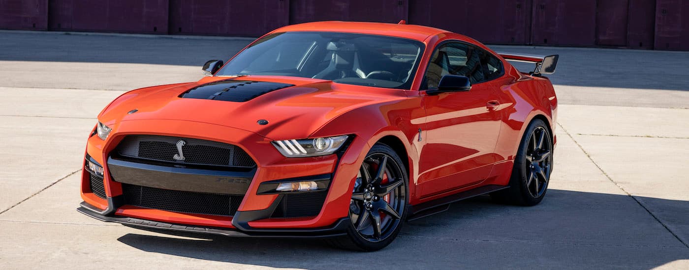 An orange 2022 Ford Mustang Shelby GT500 is shown from an angle in an empty lot.