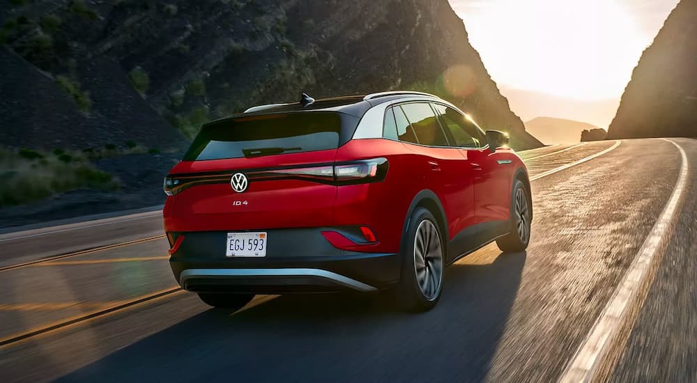 A red 2021 Volkswagen ID.4 is shown driving on an open road after looking at used EVs for sale near you.