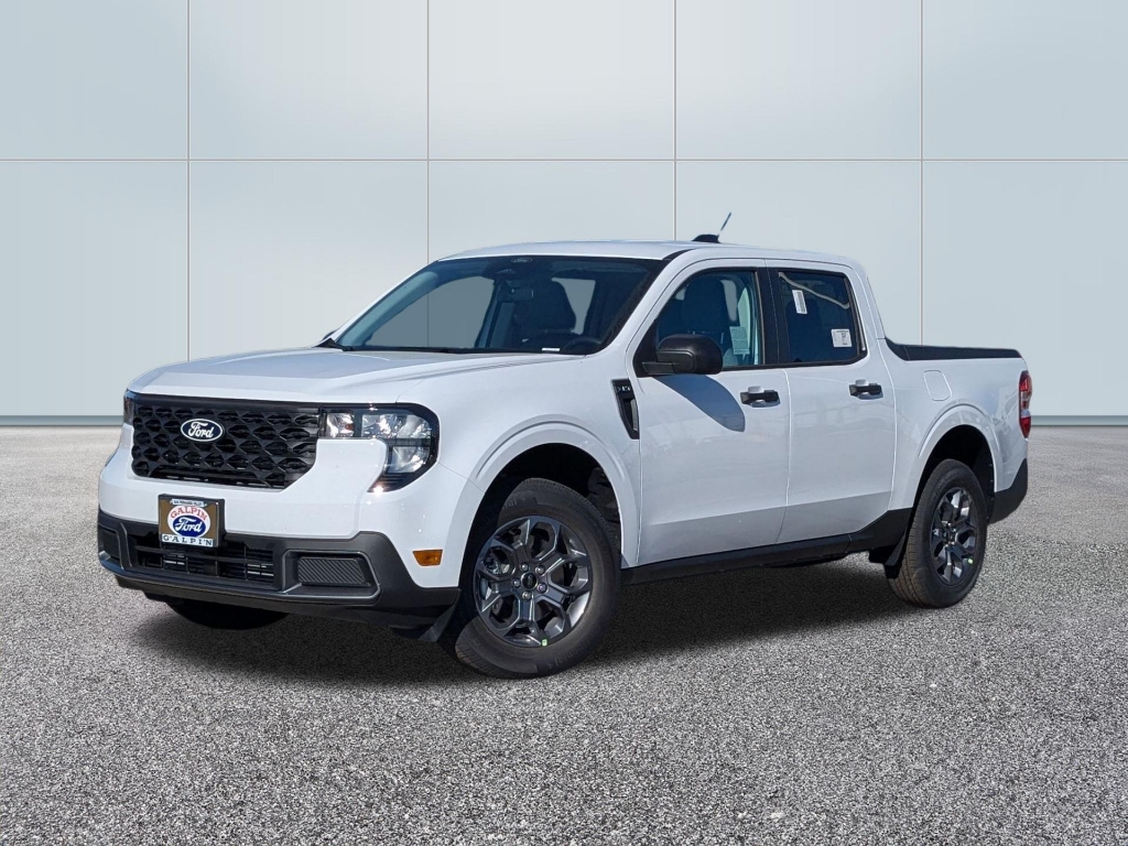 Front three-quarter view of a new 2026 Ford Maverick XLT in Oxford White. The truck features the 2025/2026 refreshed front fascia, including sleek '7-shaped' LED projector headlights and a redesigned black mesh grille with the traditional blue Ford oval badge. It is equipped with 17-inch painted aluminum wheels and black trim accents on the mirrors and door handles. The compact pickup is parked on a dealership lot against a clean, white paneled background.