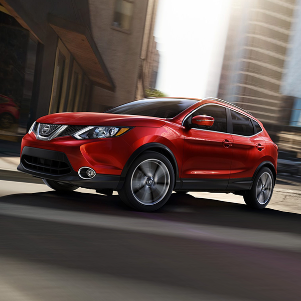 red Rogue Sport turning a corner on a city street