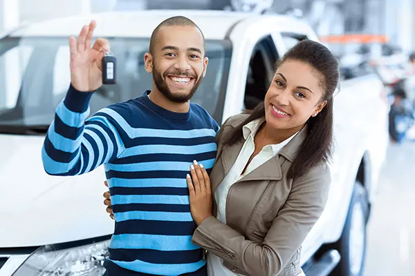 two happy people at a dealership