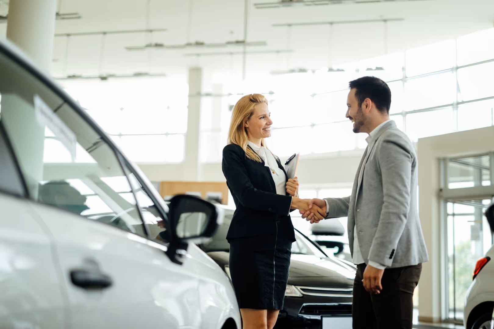 Businessman and woman shaking hands in dealershipY